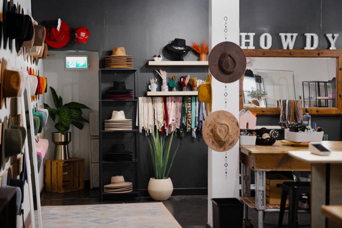 Inside the Saddle N Spurs shop — HOWDY sign, hat shelves, and ribbon wall